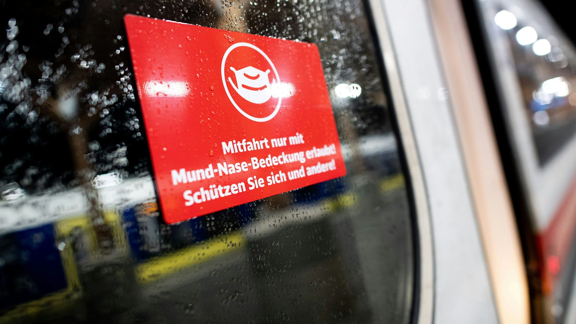 Ein Schild mit der Aufschrift „Mitfahrt nur mit Mund-Nase-Bedeckung erlaubt! Schützen Sie sich und andere!“ - klebt an der Tür eines Zuges der Deutschen Bahn.