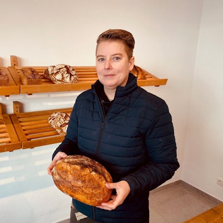 Die neue Inhaberin hält ein Brot in der Hand.