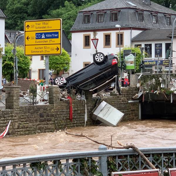 Nach dem Hochwasser am 14. Juli 2021 hängt ein Auto kopfüber an einem Geländer in Gemünd.