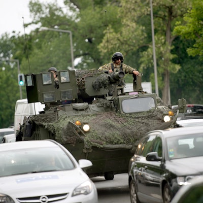 Ein Panzer der US-amerikanischen Streitkräfte ist auf einer Straße unterwegs. Ein Soldat mit Sonnenbrille sitzt auf dem Geschützturm. Um den Panzer herum fahren Autos (Symbolbild)