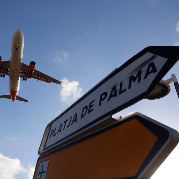 ARCHIV - 18.08.2020, Spanien, Palma: Ein Flugzeug überfliegt bei der Landung auf Mallorca ein Schild, das die Richtung nach Playa de Palma anzeigt.