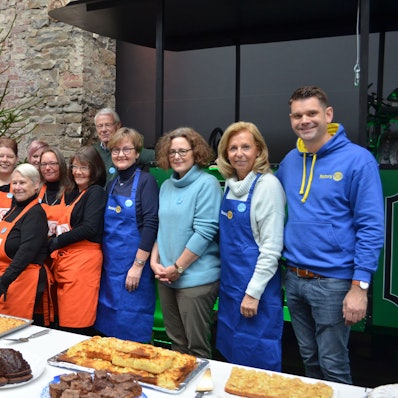 Mitglieder der Rotarier und der Tafel stehen vor einem Kuchenbuffet.