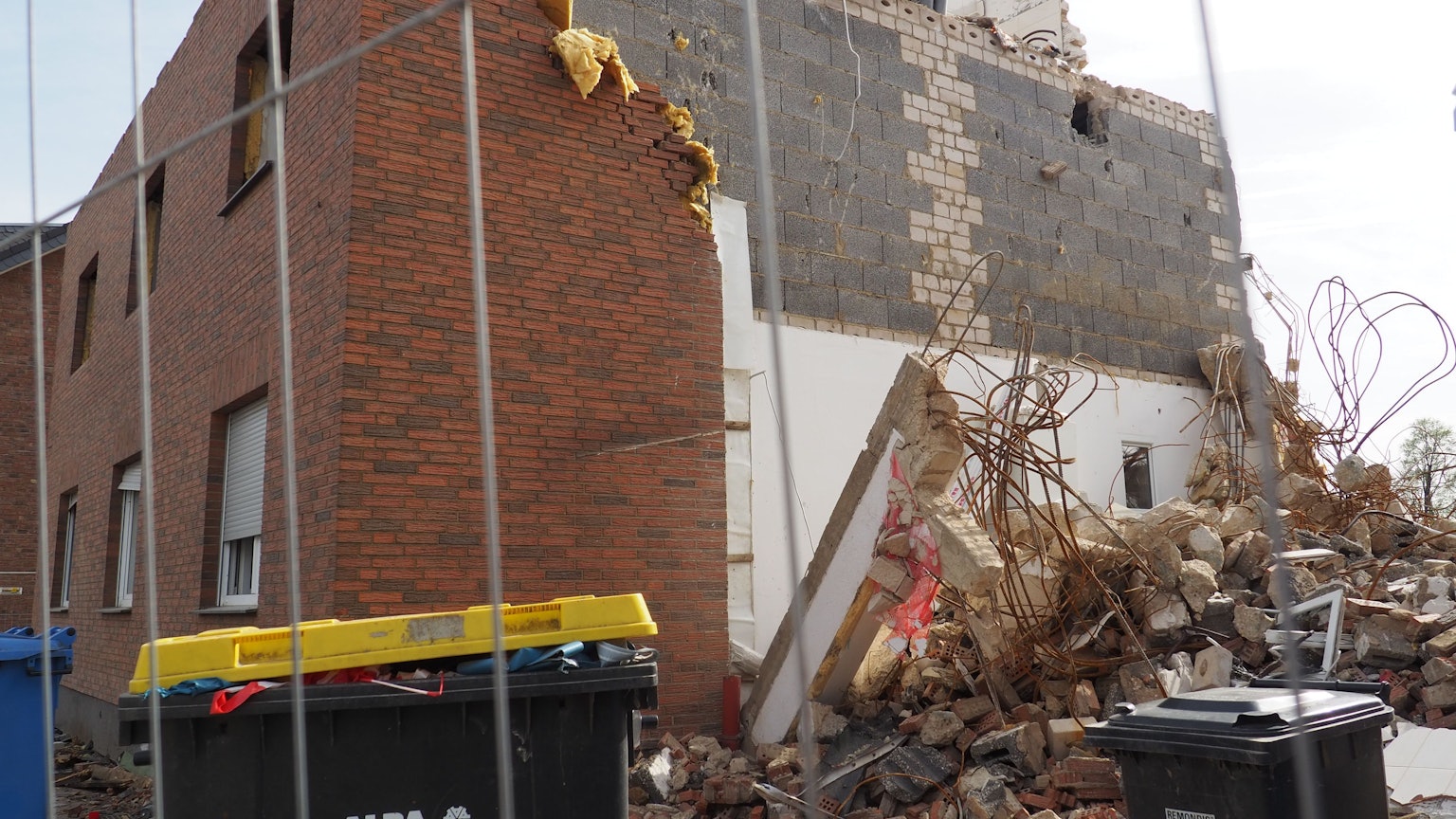 Ein zerstörtes Haus nach der Flut, davor steht ein Bauzaun.