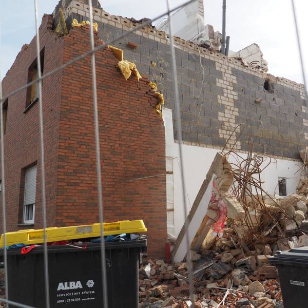 Ein zerstörtes Haus nach der Flut, davor steht ein Bauzaun.