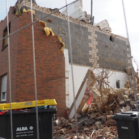 Ein zerstörtes Haus nach der Flut, davor steht ein Bauzaun.