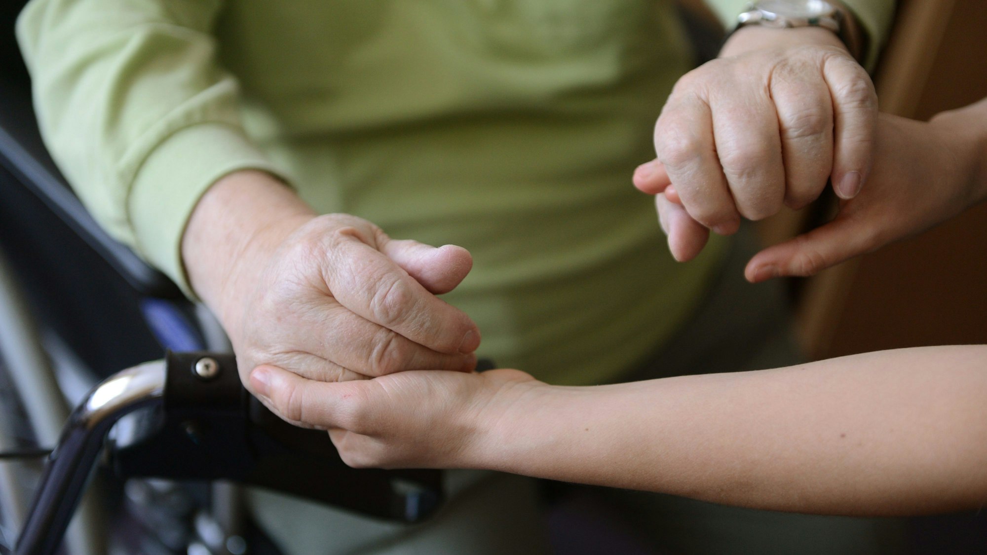 ILLUSTRATION - 05.12.2012, Berlin: Eine junge Frau hält die Hände eines alten Mannes.