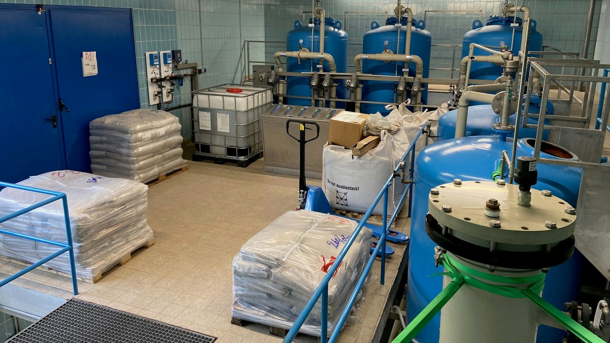 Eine Halle, in der mehrere große Tanks stehen. Im Vordergrund stehen Paletten.