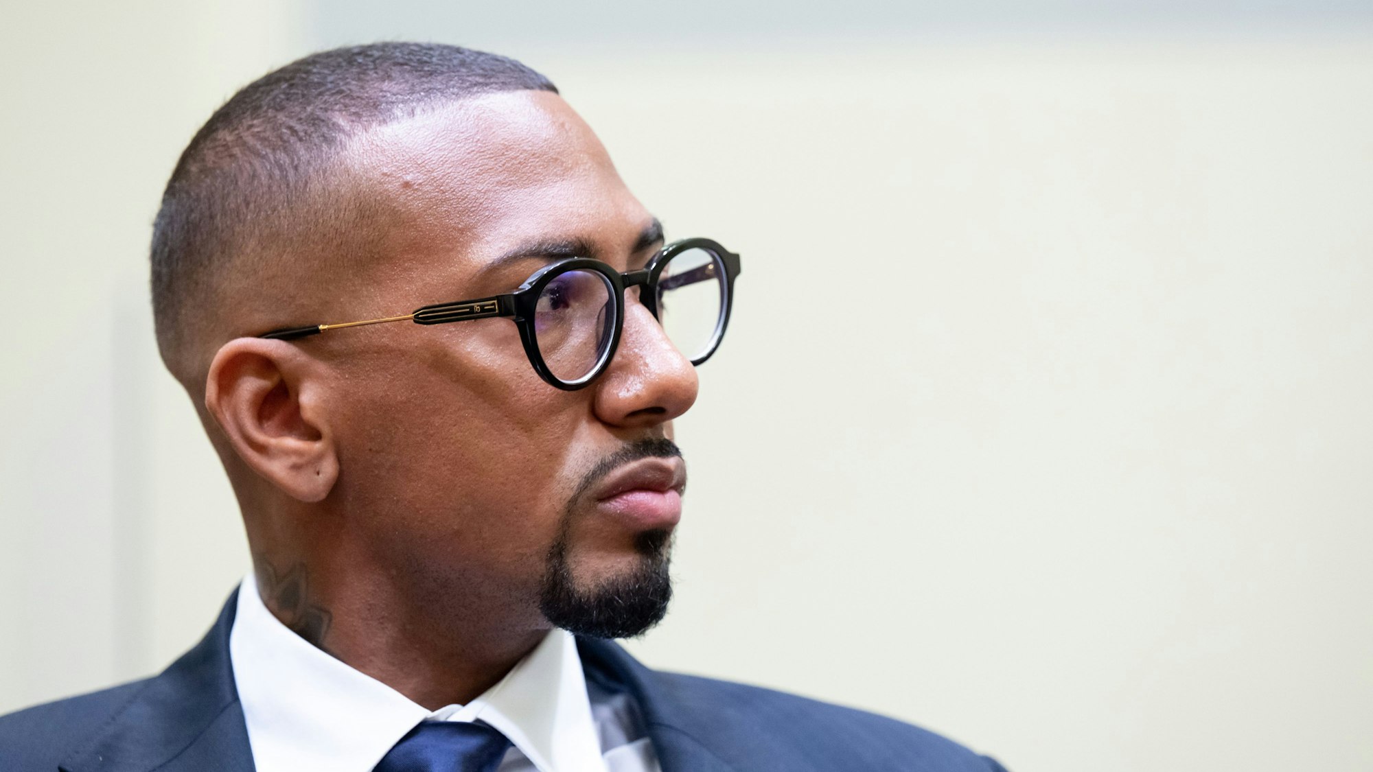 Der Fußball-Profi und ehemalige Nationalspieler Jerome Boateng trägt einen Anzug und Brille und schaut zur Seite.