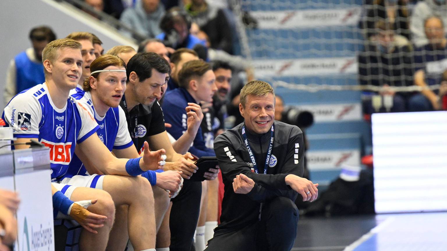 Trainer des Vfl Gummersbach sitzt vor der Bank der Mannschaft in der Hocke.
