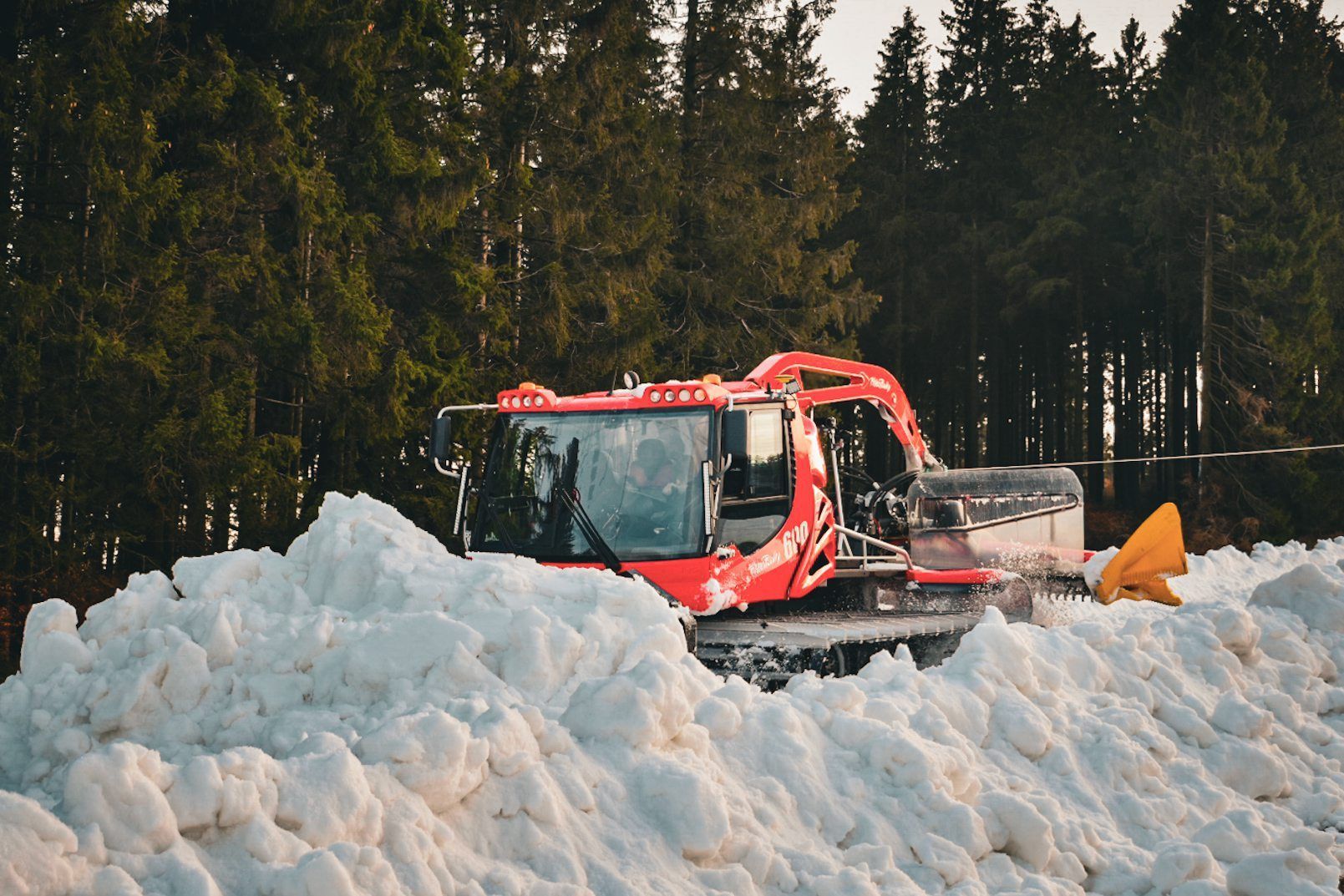 Nordrhein-Westfalen, Winterberg: Eine Pistenraupe verteilt im Skiliftkarussell technisch erzeugten Schnee auf einer Piste.