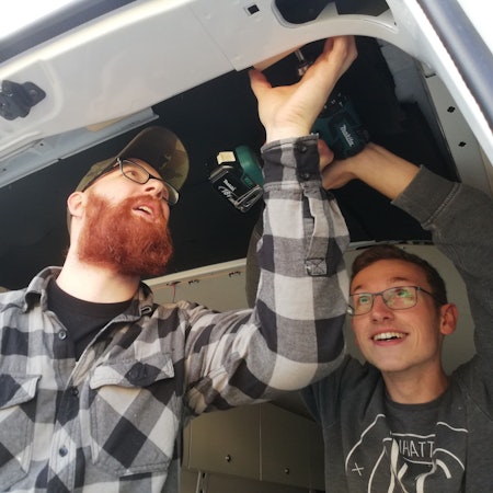 Zwei Tischlerazubis des Berufskollegs Bergisch Gladbach schrauben an der Innenseite des Bergisch Gladbacher Kältebusses.