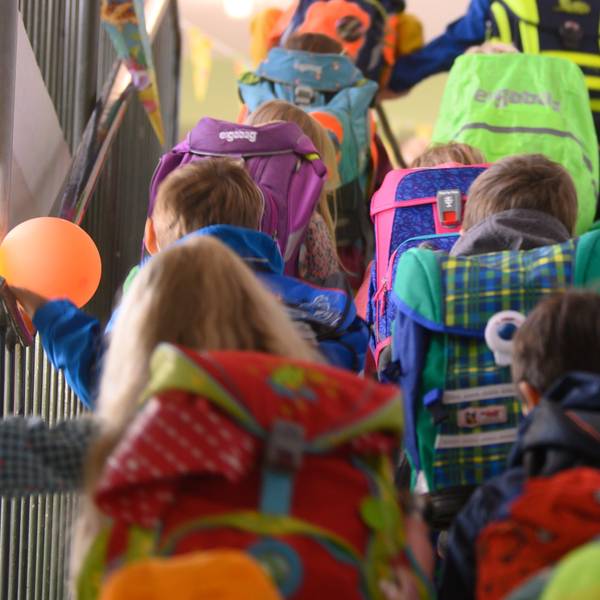 Auf dem Bild sind Kinder mit Schulranzen von hinten zu sehen. Sie gehen eine Treppe hinauf. (Symbolbild)
