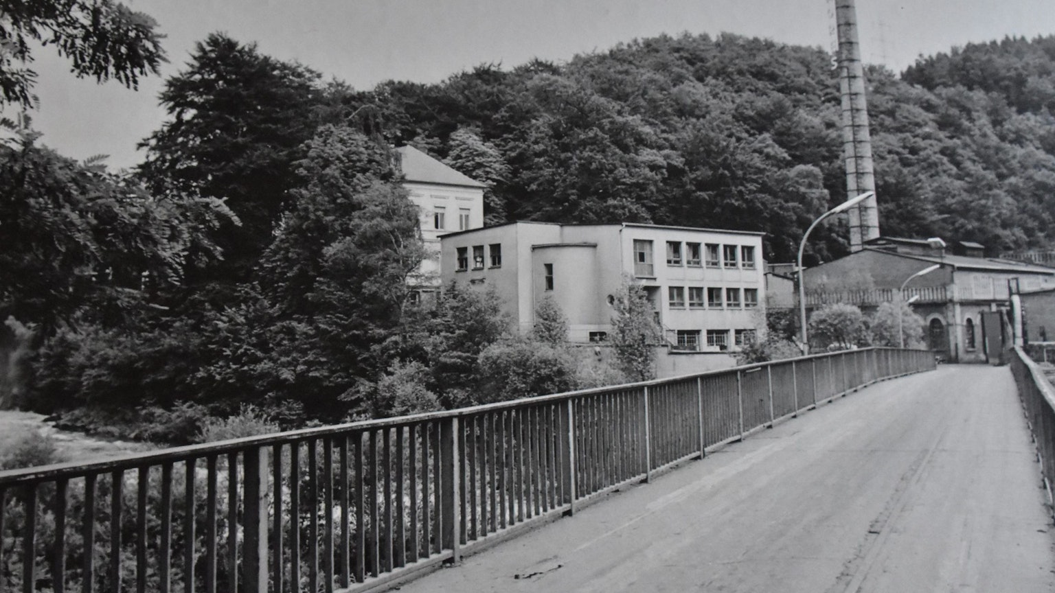 Ein Bild in schwarzweiß zeigt eine Brücke und mehrere Gebäude.