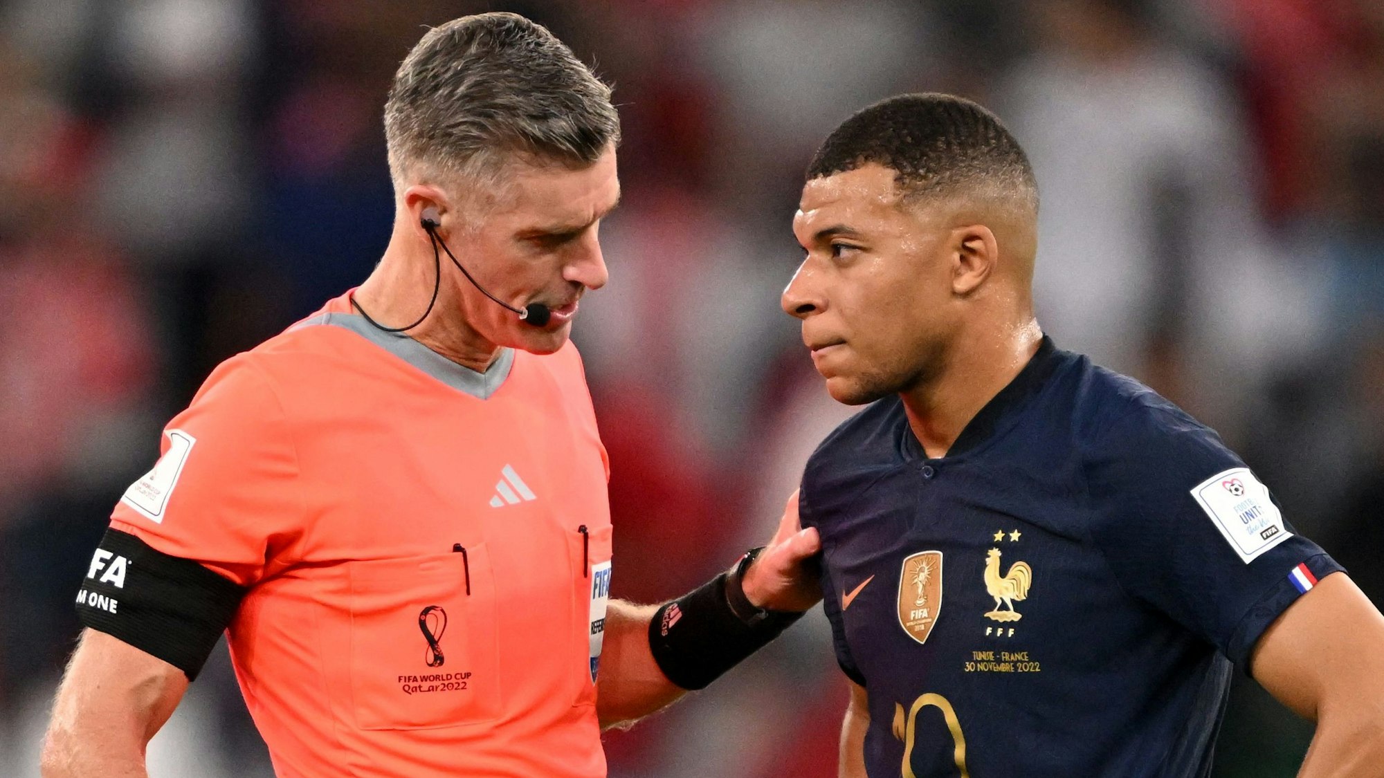 Schiedsrichter Matthew Conger spricht mit Frankreichs Nationalstürmer Kylian Mbappe auf dem Rasen. Conger greift Mbappe an die Schulter.