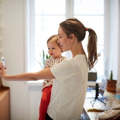 Influencerin nimmt ein Selfie mit ihrer Tochter auf Symbolbild.
