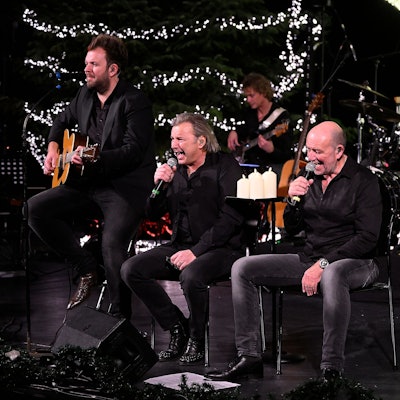 Musiker der Paveier musizieren vor einem leuchten Weihnachtsbaum.