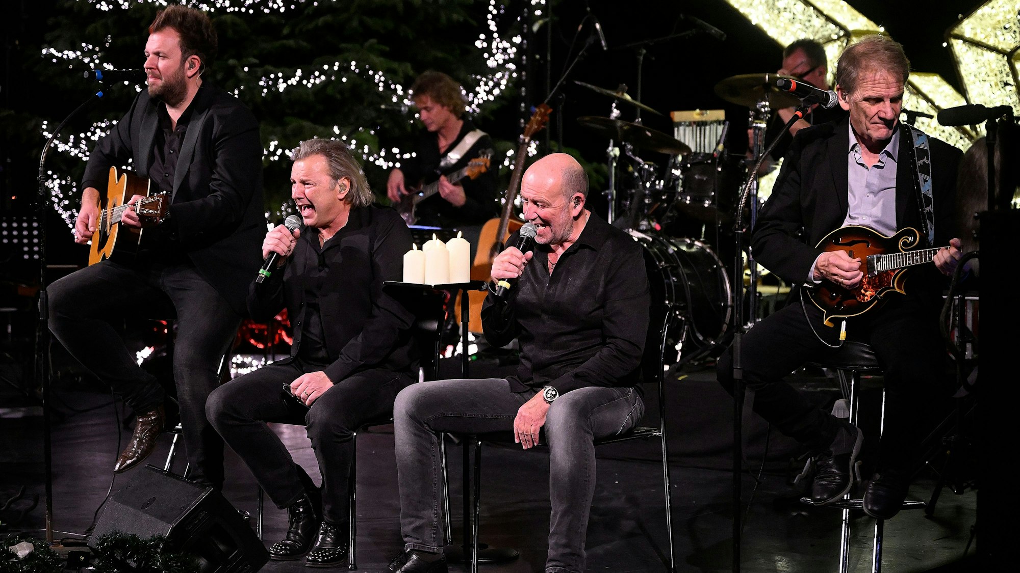 Musiker der Paveier musizieren vor einem leuchten Weihnachtsbaum.