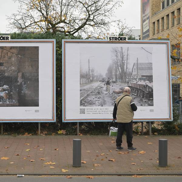 Ein Mann steht vor den beiden großformatigen Bildern, die in Bergisch Gladbach gegenüber dem Busbahnhof hängen.