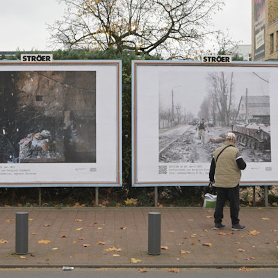 Ein Mann steht vor den beiden großformatigen Bildern, die in Bergisch Gladbach gegenüber dem Busbahnhof hängen.