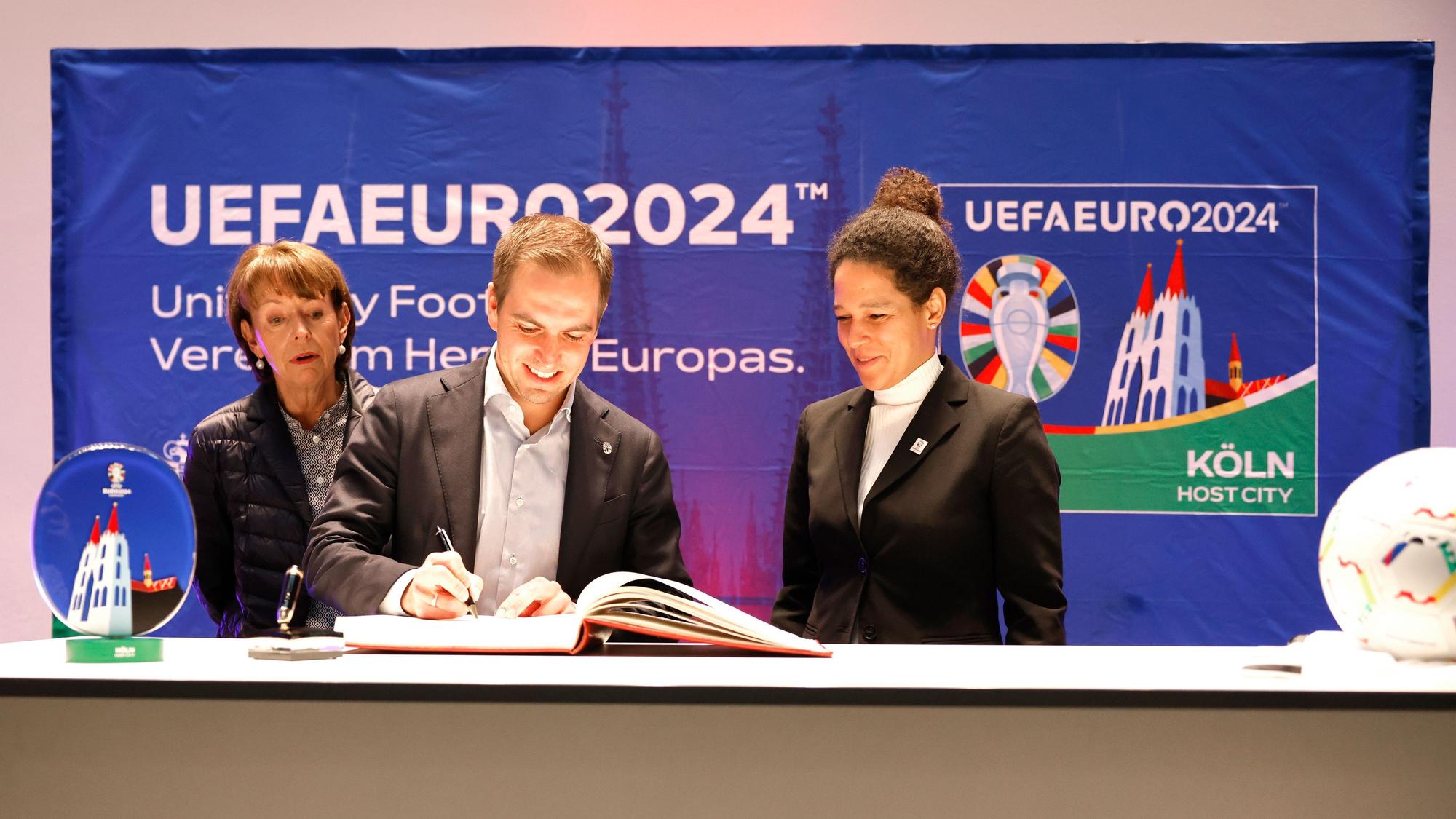 Turnierdirektor Philipp Lahm und DFB-Vizepräsidentin Celia Sasic tragen sich im Beisein von Oberbürgermeisterin Henriette Reker (l.) ins Gästebuch der Stadt ein.