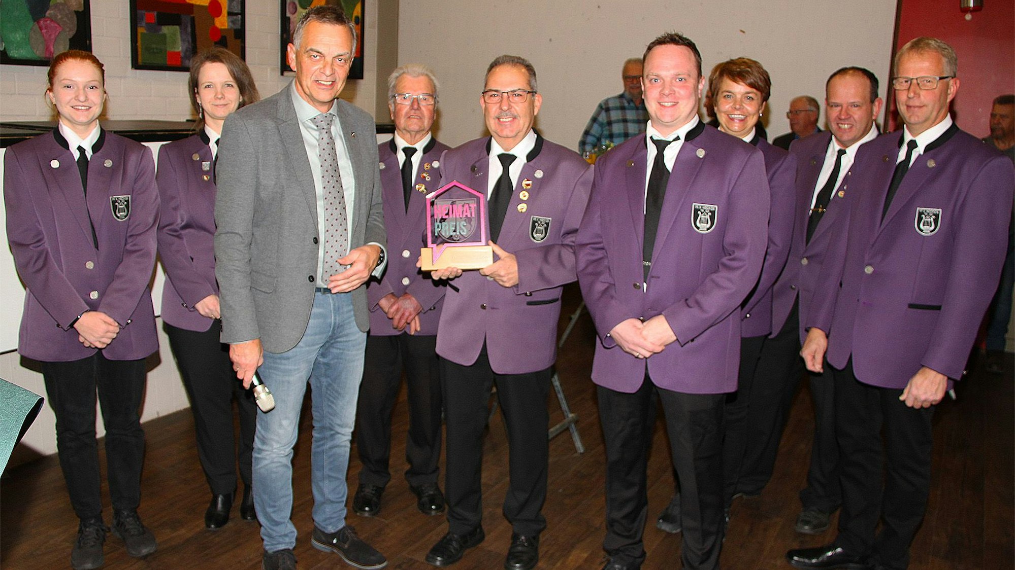 Das Foto zeigt den Hellenthaler Bürgermeister Rudolf Westerburg, der die Skulptur des Heimatpreises Richard Hoven und weitere Vertreter des Musikvereins Hecken überreicht.