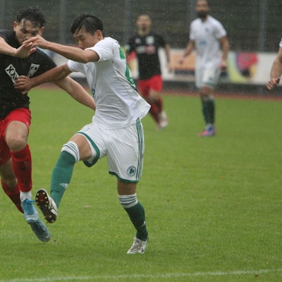 Der Hennefer Akteur Johannes Siregar sprintet dem Ball hinterher und hält sich seinen Gegenspieler mit Armeinsatz vom Leib.