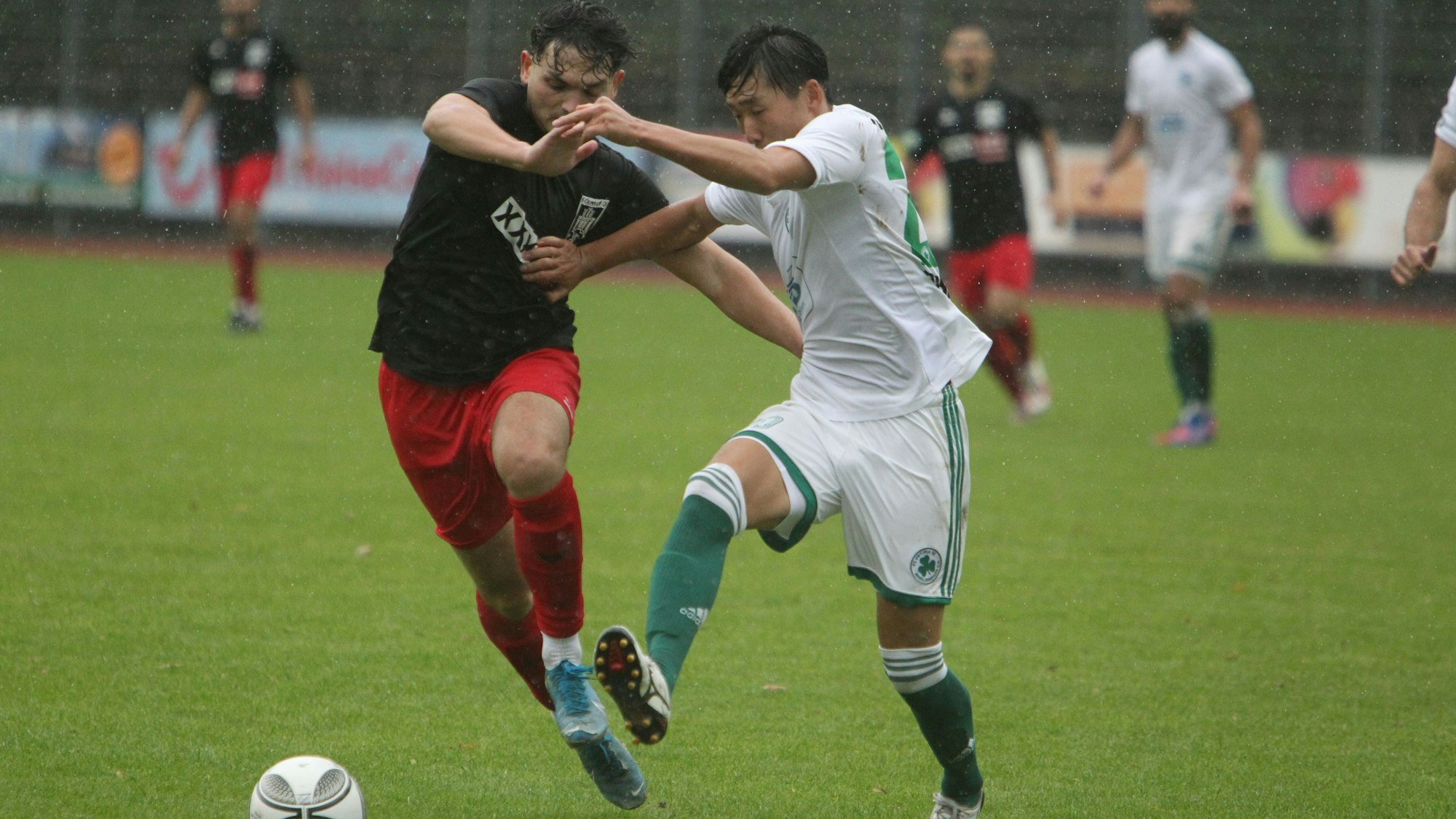 Der Hennefer Akteur Johannes Siregar sprintet dem Ball hinterher und hält sich seinen Gegenspieler mit Armeinsatz vom Leib.