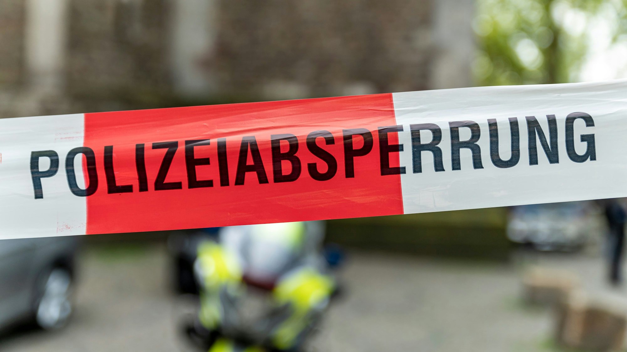 Flatterband einer Polizeiabsperrung, auf dem rot-weißen Band steht in schwarzen Buchstaben Polizeiabsperrung.
