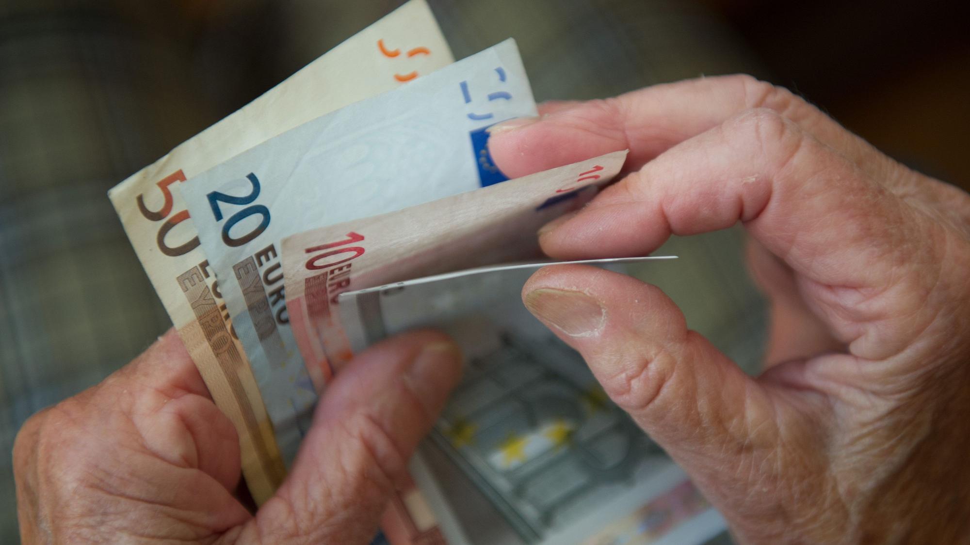 Eine ältere Frau zählt Geld.
