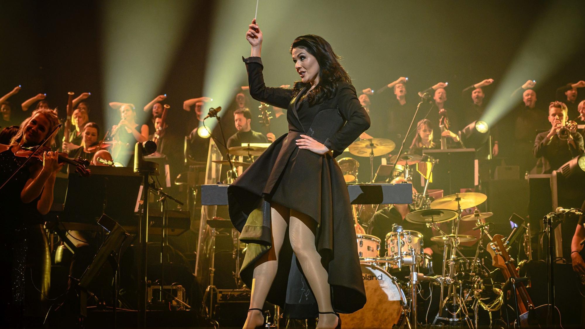Ein Hauch von Alice im Wunderland: Dirigentin Alexandra Arrieche hat das Publikum und das Antwerp Philharmonic Orchestra gleichermaßen gut im Griff. In einem schwarzen kurzen Mantelkleid mit knöchellanger weiter Schleppe fegte sie auf hohen Schuhen über die Bühne.