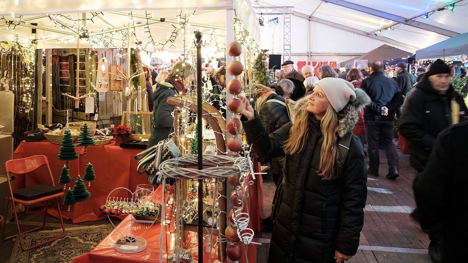 In einem auch mit Lichtern dekorierten Zelt schauen Besucher nach weihnachtlicher Dekoration.