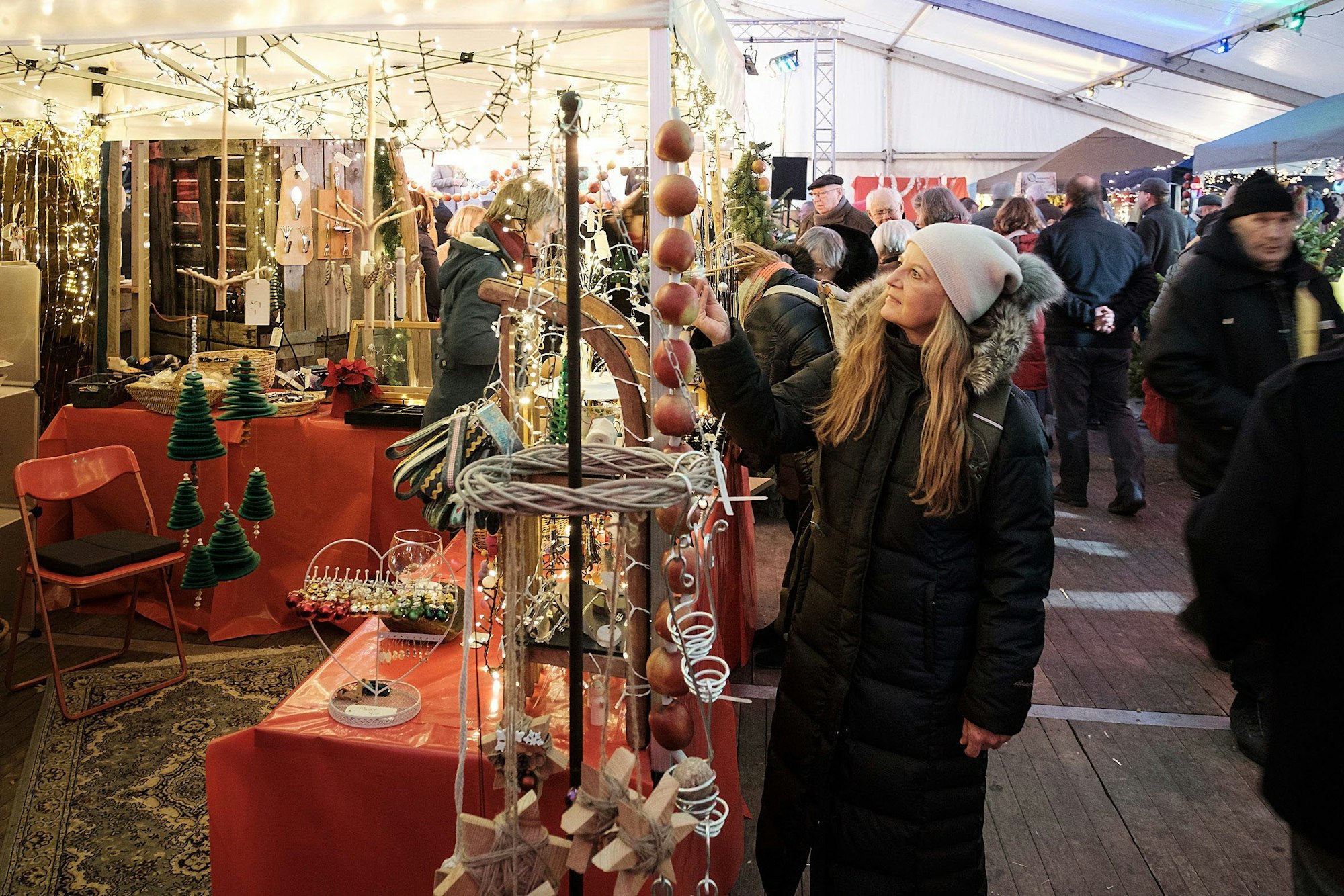 In einem auch mit Lichtern dekorierten Zelt schauen Besucher nach weihnachtlicher Dekoration.