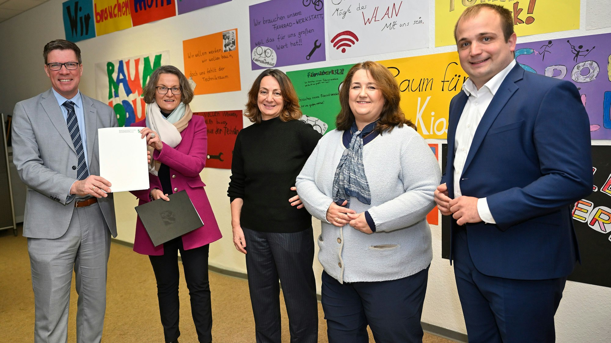 Ministerin Ina Scharrenbach übergibt Rhein-Bergs Landrat Stephan Santelmann einen Bescheid über Wiederaufbaumittel in der Albert-Einstein-Schule.