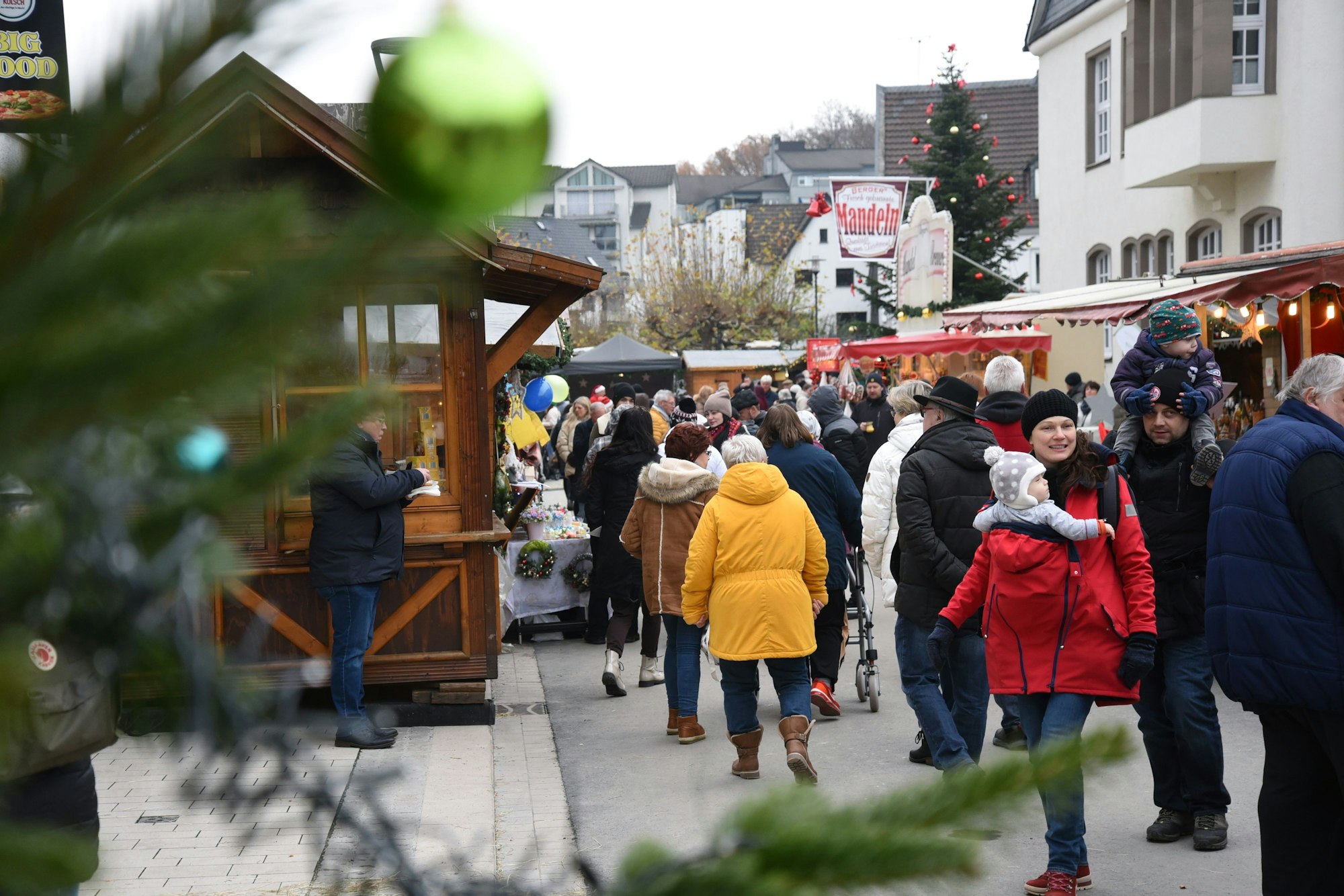 Blick auf den Vorplatz des Wiehler Rathauses, wo Menschen zwischen den Holzbunden flanieren.