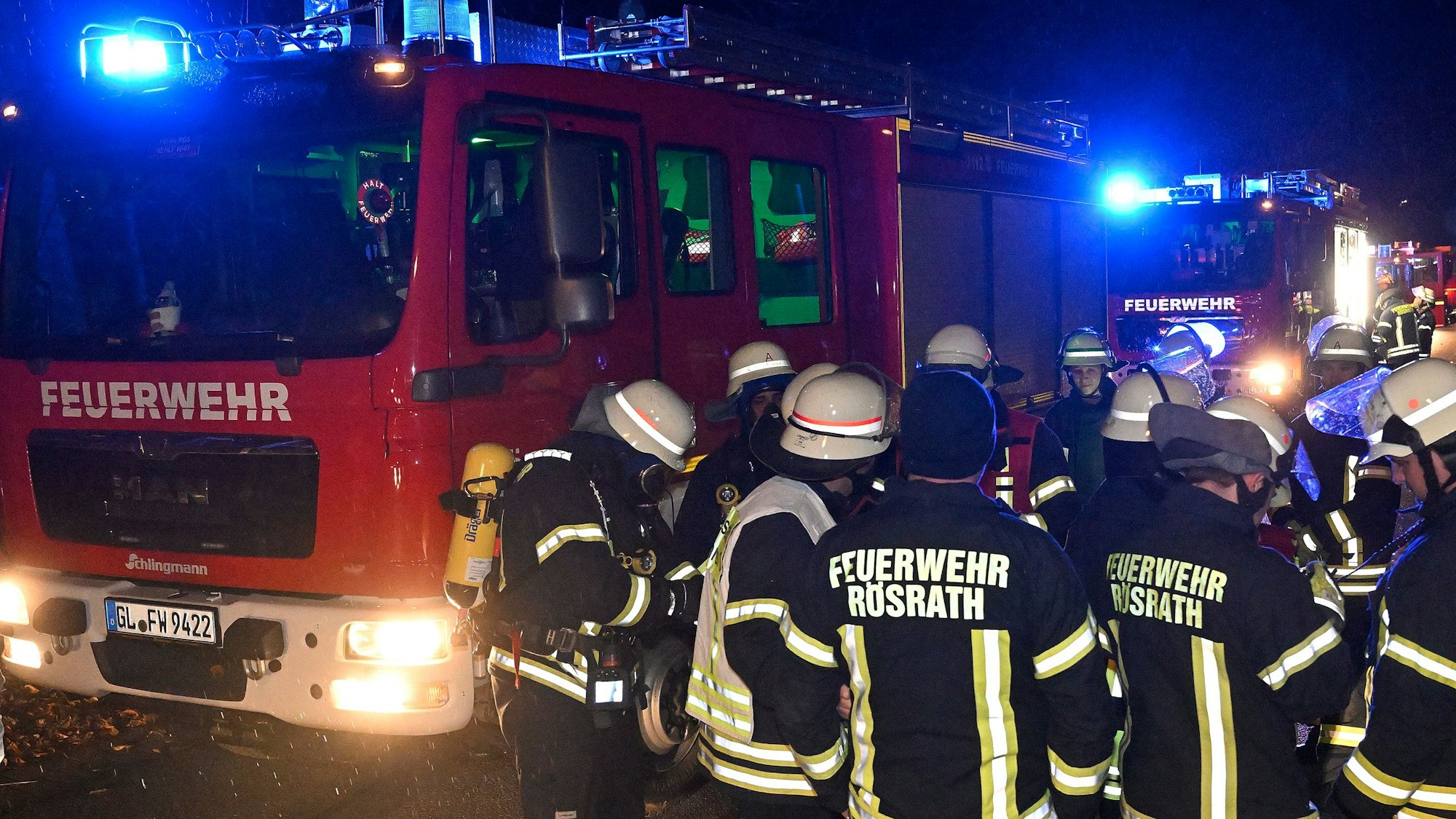 Rösrather Feuerwehrleute stehen bei Nacht vor einem Einsatzfahrzeug.