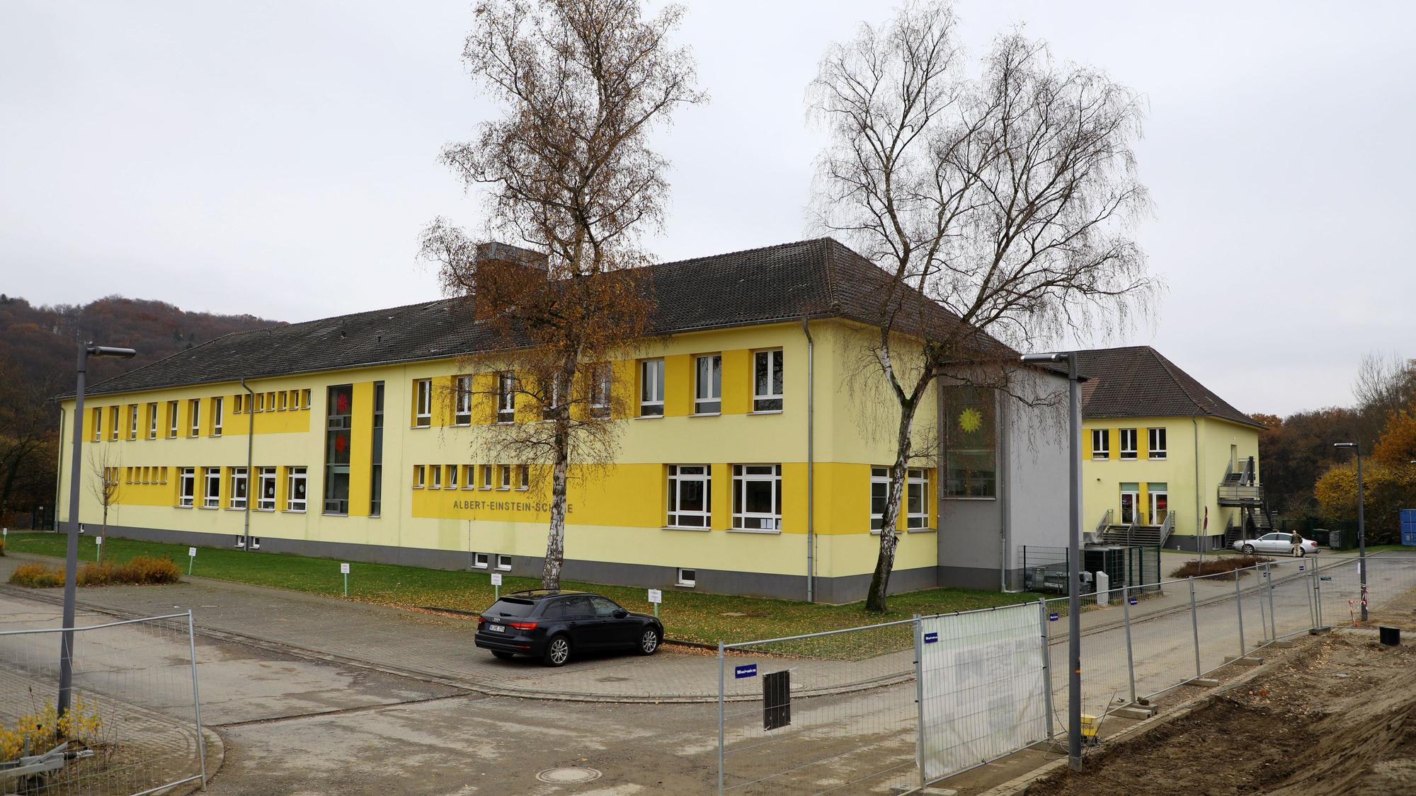 Vor zwei Schulgebäuden parkt ein Auto, die Gebäude sind frisch gestrichen.