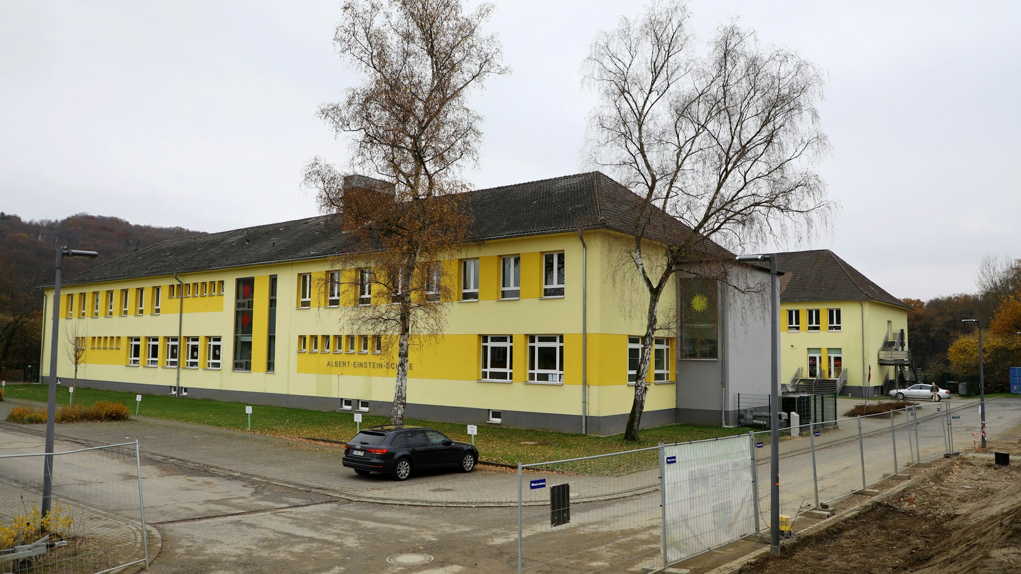 Vor zwei Schulgebäuden parkt ein Auto, die Gebäude sind frisch gestrichen.