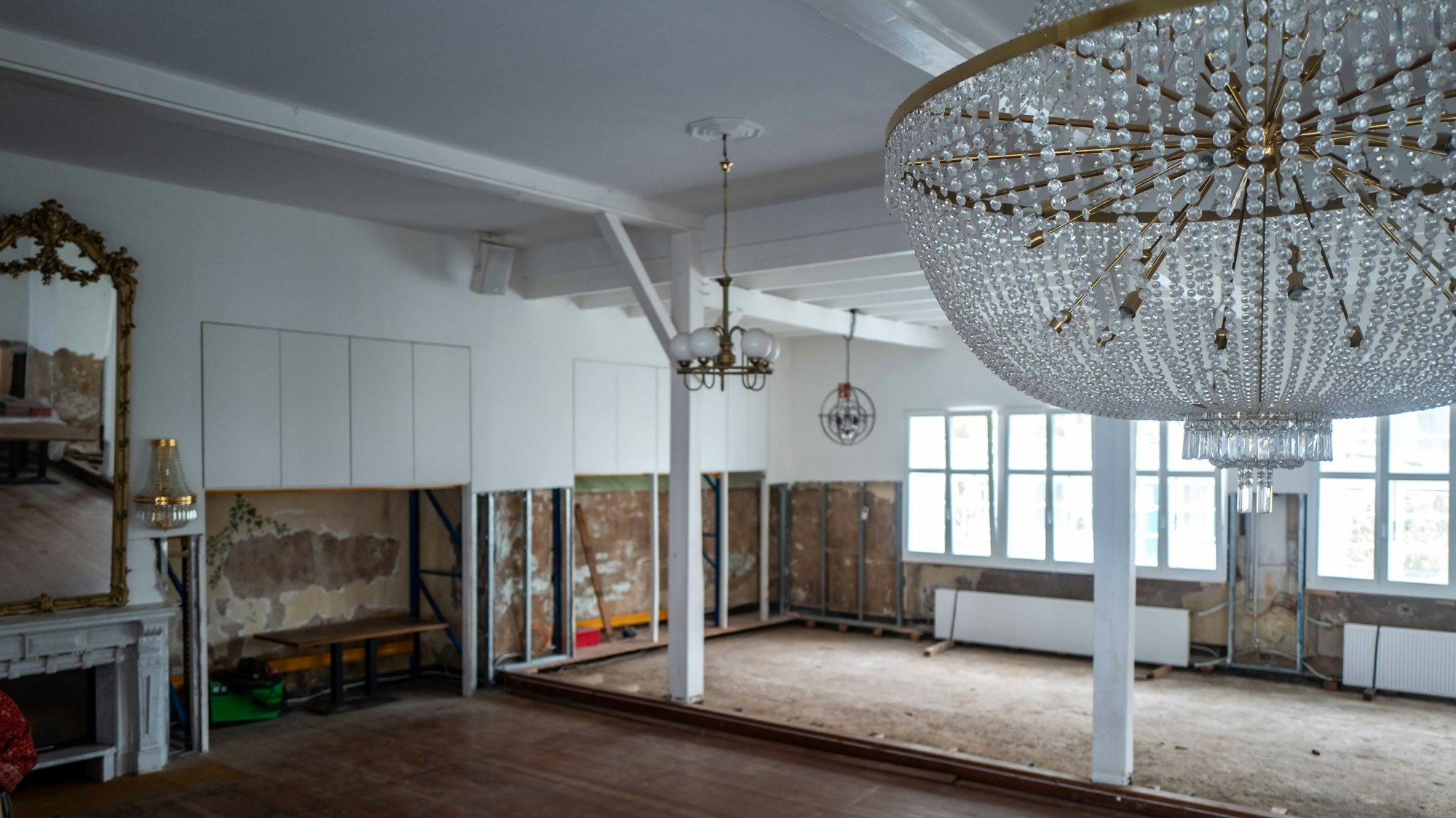 Im Saal des Brauhauses sind die Schäden, die die Flut verursacht hat, noch gut sichtbar. Im Vordergrund hängt ein Leuchter, im Hintergrund sind die Wände nach der Flut immer noch aufgerissen.