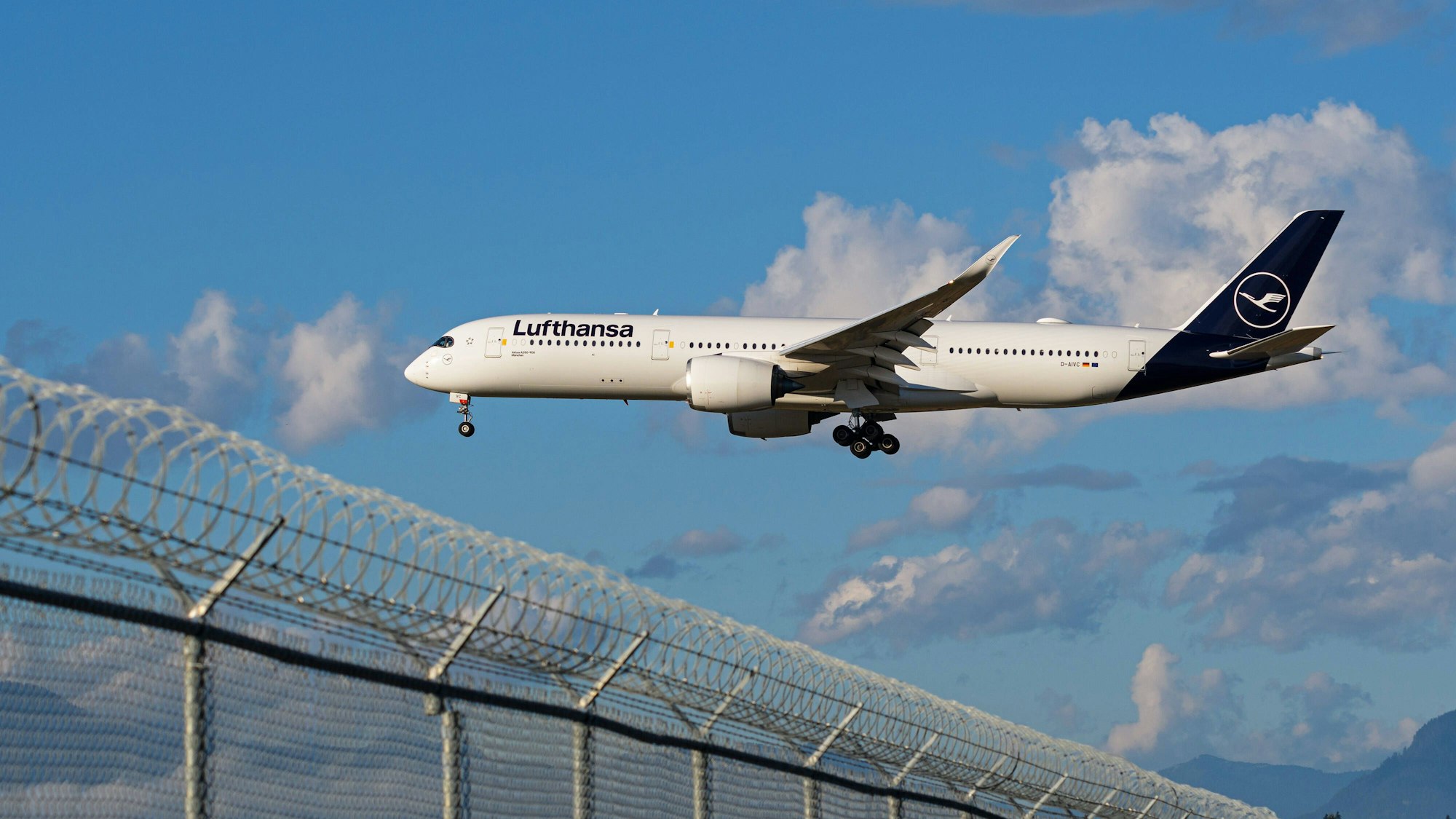 Ein A350-900-Flugzeug fliegt über einen Zaun.