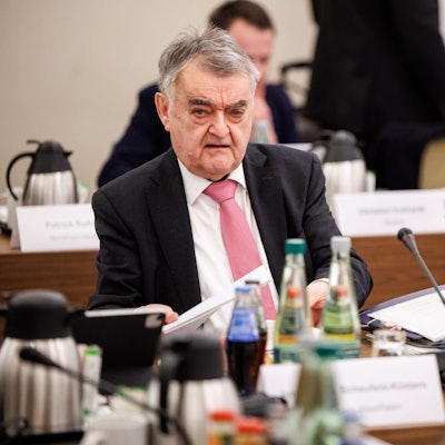 NRW-Innenminister Herbert Reul sitzt im Anzug bei einer Konferenz.