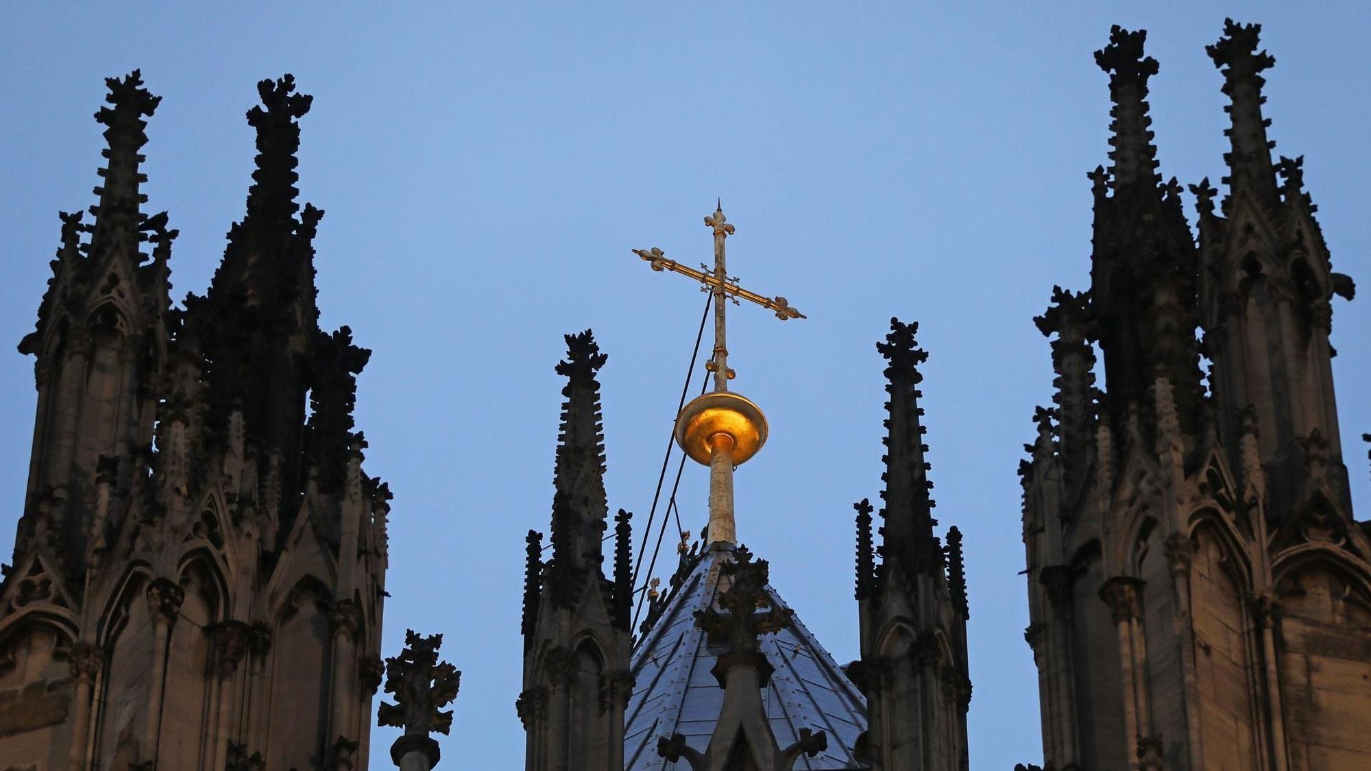 Ein Kreuz steht hinter dem Strebewerk am Dom.
