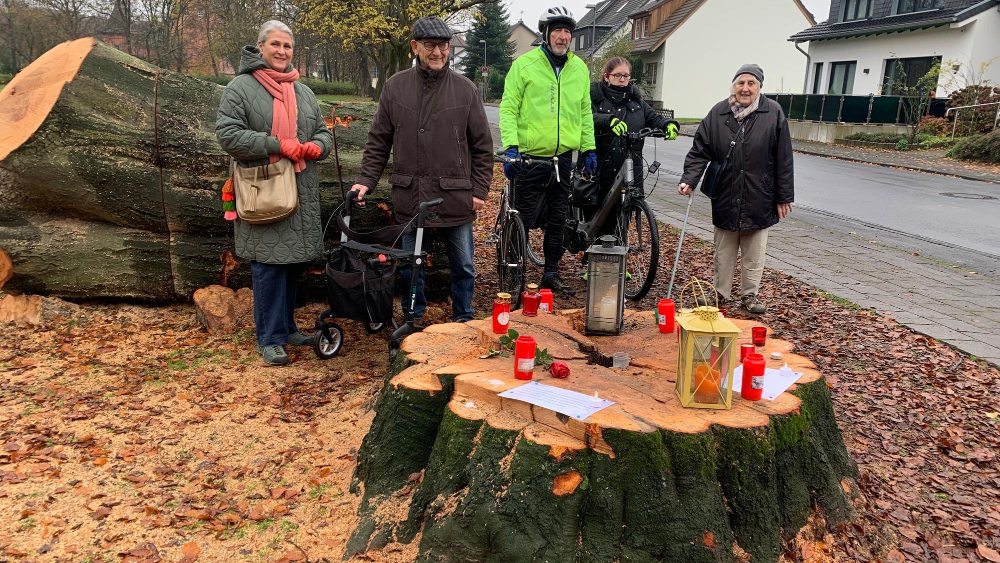 Anwohner aus Spich stehen rund um abgesägten Baumstumpf.