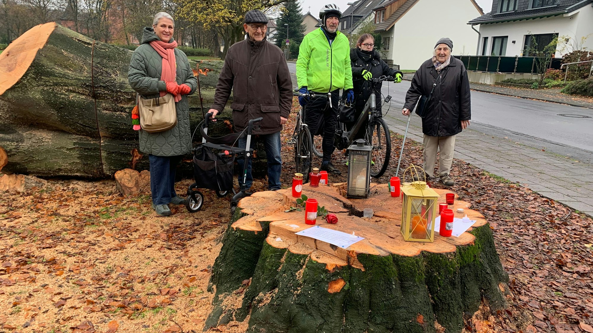 Anwohner aus Spich stehen rund um abgesägten Baumstumpf.