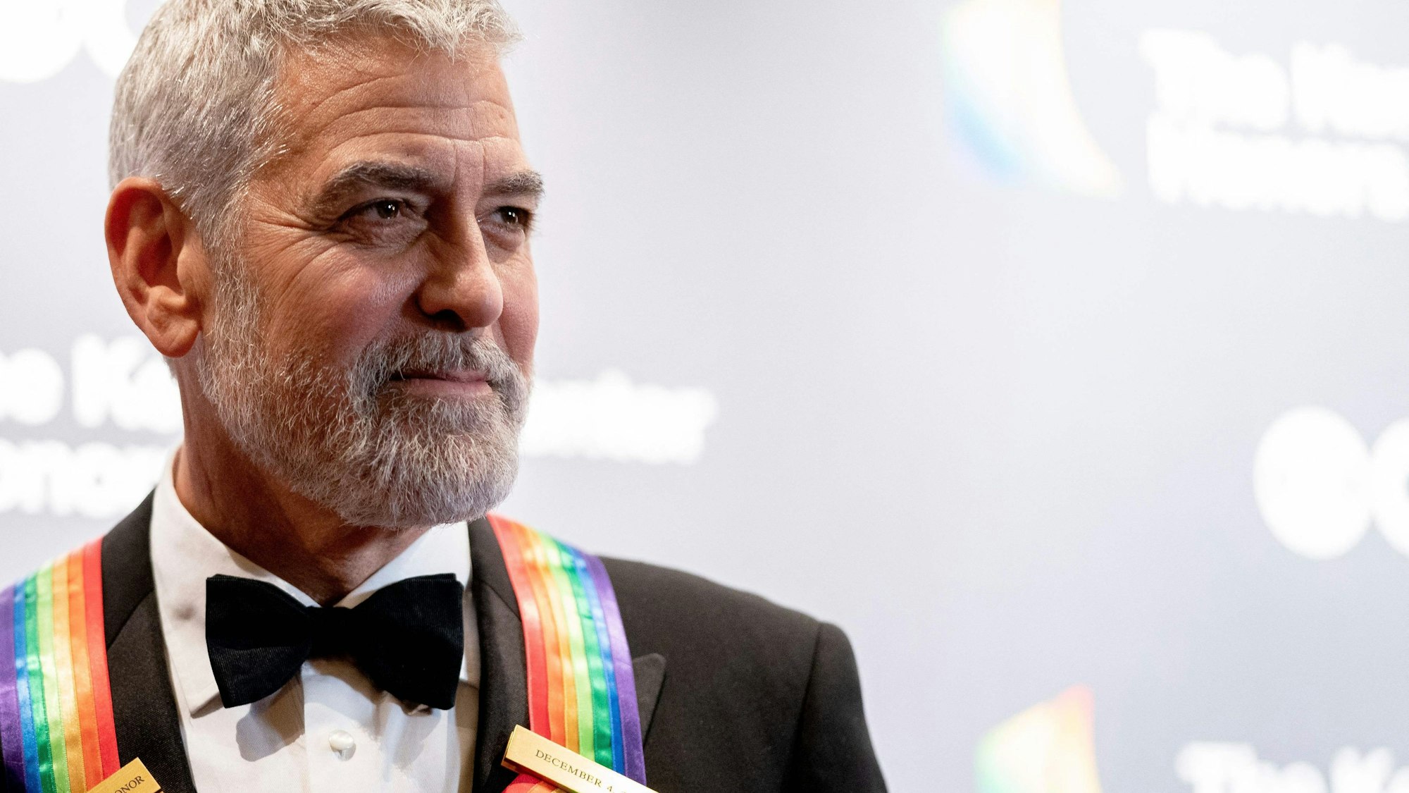 George Clooney bei den 45. Kennedy Center Honors im John F. Kennedy Center for the Performing Arts in Washington, DC. Er trägt seine Auszeichnung mit Regenbogen-Band um den Hals. Er trägt einen schwarzen Anzug.