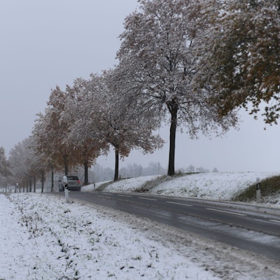 Neben einer Landstraße im Rhein-Seig-Kreis sind die umliegenden Wiesen mit Schnee bedeckt.