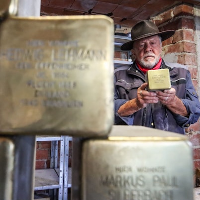 Künstler Gunter Demnig hält einen seiner Stolpersteine in der Hand.
