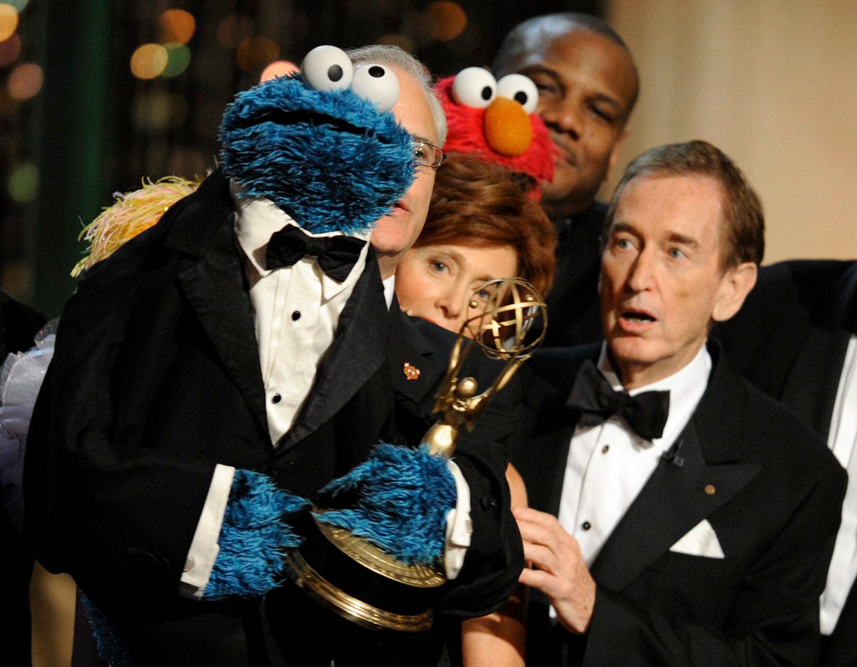 Schauspieler Bob McGrath steht im Smoking neben der Sesamstraßen-Figur Krümelmonster. Krümelmonster hält einen Preis, der für die Show bei einer Preisverleihung überreicht wurde.