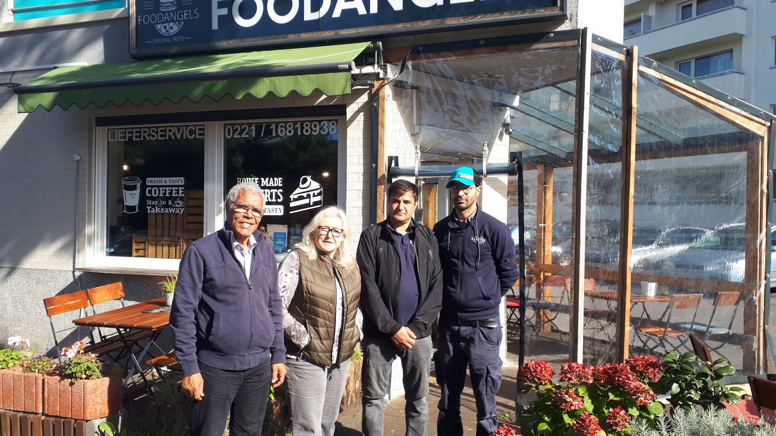 Najib Ramz, Susanna Zeltinger, der betroffene Fazal Rabi Rahimzai und 'Foodangels'-Betreiber Mazlom Sediqi stehen vor dem Restaurant „Foodangels“ in Köln.