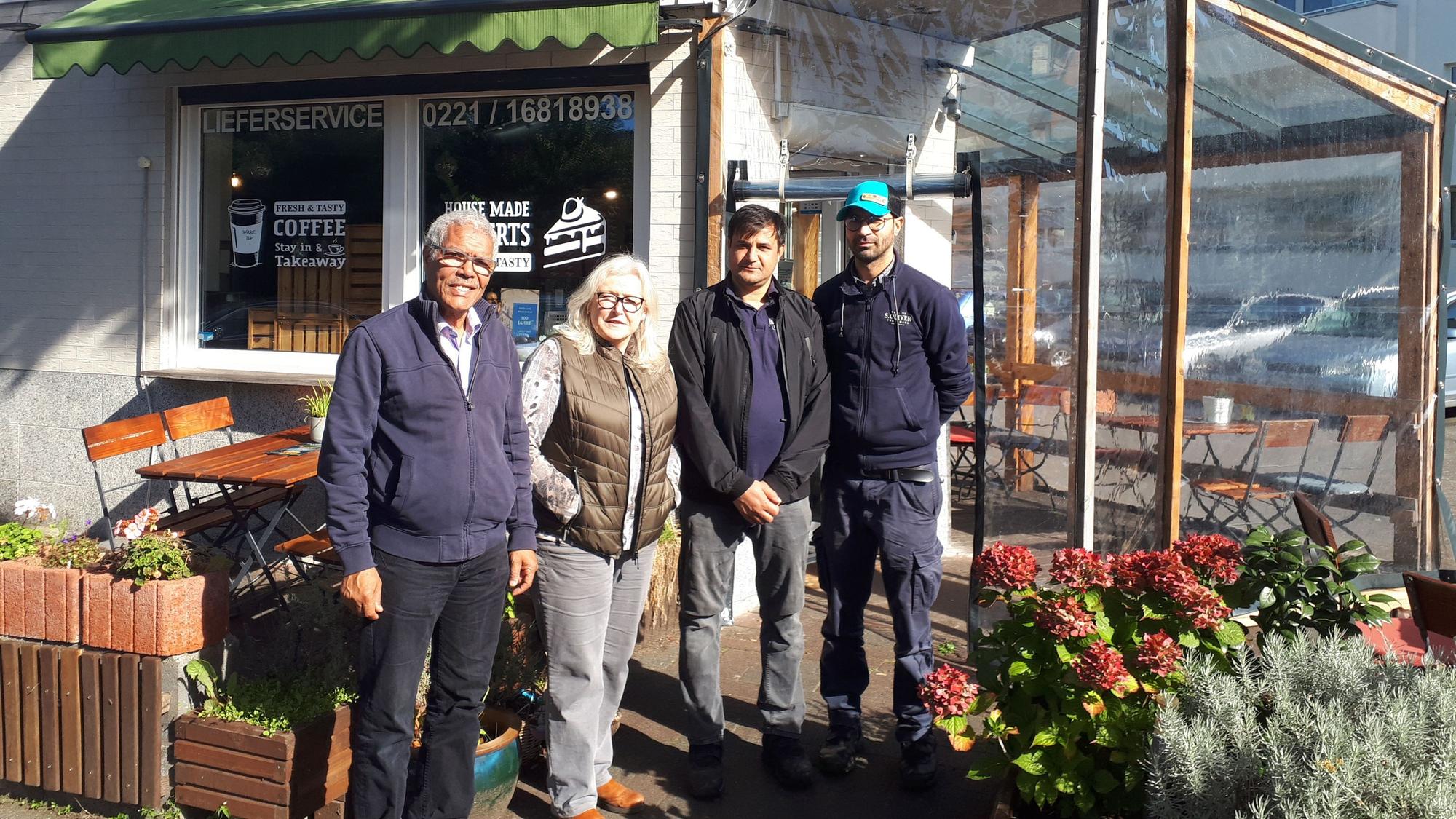 Najib Ramz, Susanna Zeltinger, der betroffene Fazal Rabi Rahimzai und 'Foodangels'-Betreiber Mazlom Sediqi stehen vor dem Restaurant „Foodangels“ in Köln.