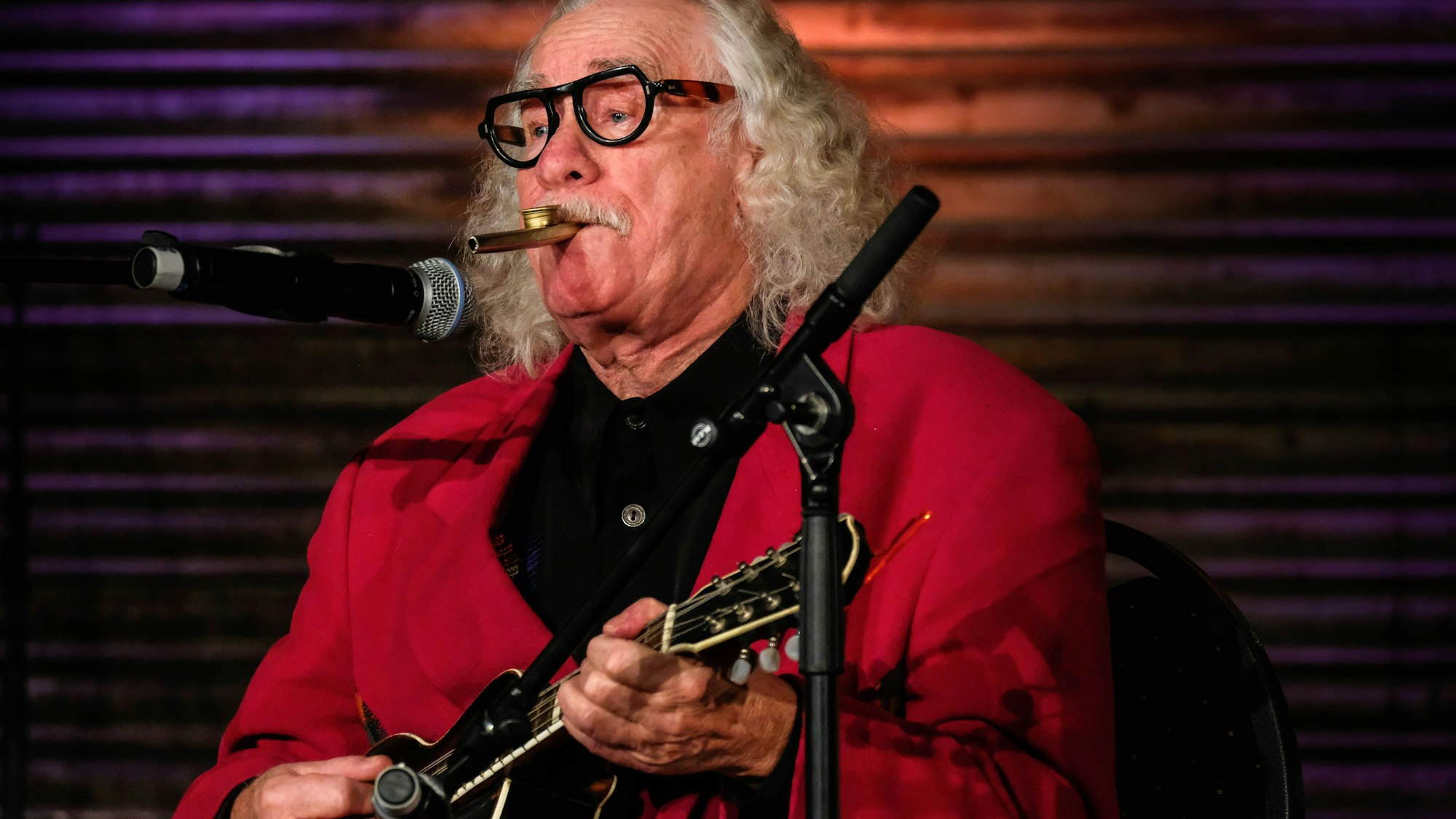 Hans Süper spielt Gitarre bei einem Auftritt.